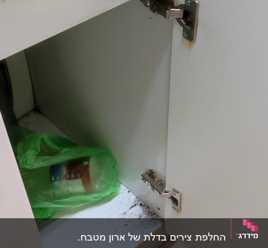 ארון מטבח פתוח עם צירים חשופים ולכלוך בפנים